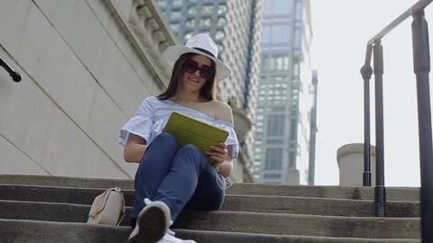 Beautiful female is working with tablet pc sitting on street stairs. Stock Footage 104313610