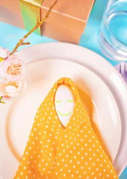 Beautiful festive Easter table setting with yellow napkin polka dot and smili Stock Photos