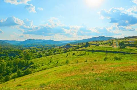 Beautiful fields against the backdrop of mountains and blue sky with clouds. Stock Photos