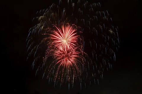 Beautiful fiery rays of light from explosion of pyrotechnics on black background Foto stock