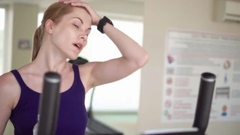 Beautiful fit young woman in a gym doing exercises on a velosimulator. Drinking Stock Footage