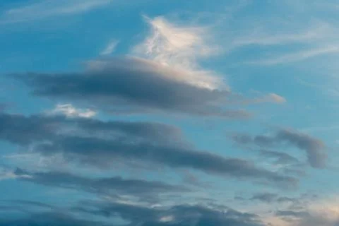 Beautiful fluffy clouds in the evening sky. The sunlight gives a side light o Stock Photos