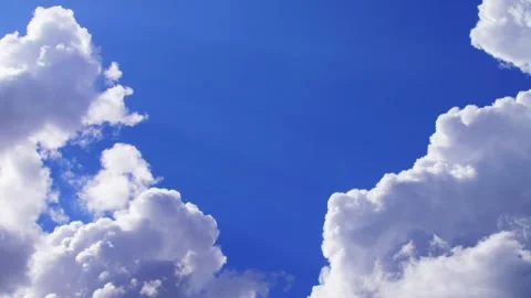 Beautiful fluffy white clouds drift across a bright clear blue sky Stock Footage 325488109