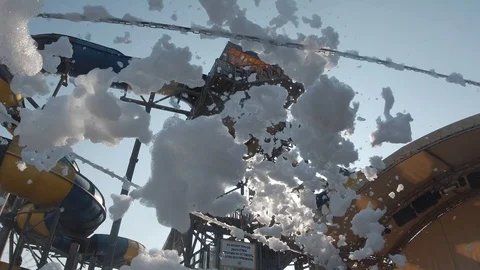 Beautiful foam flies against the backdrop of a water slide. Foam party at sunset Видео 115055167