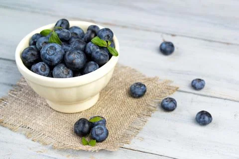 Beautiful fresh blueberries in a white ceramic bowl on a wooden background Stock Photos