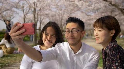 Beautiful friends taking selfies under cherry blossom trees. Stock Footage 87975218
