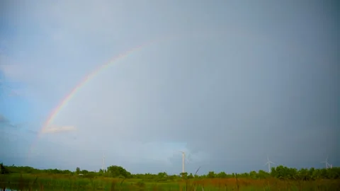 Beautiful Full Rainbow Arching Over Green Fields with Wind Turbines Against.. Stock Footage 339936406