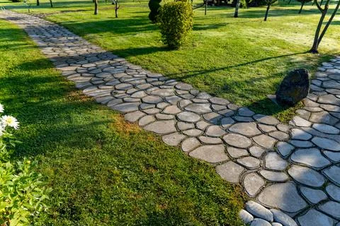 Beautiful garden path made of irregular, natural stones. The path winds throu Stock Photos
