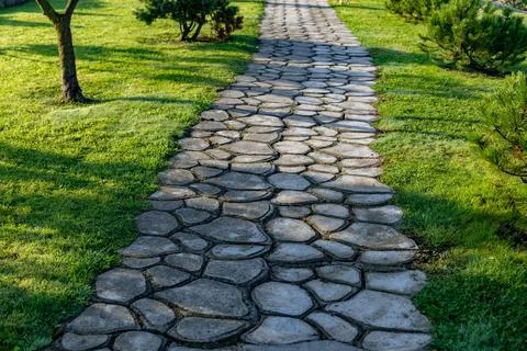 Beautiful garden path made of irregular, natural stones. The path winds throu Stock Photos
