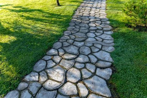 Beautiful garden path made of irregular, natural stones. The path winds throu Stock Photos