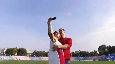 Beautiful girl and the guy doing selfie at the stadium Stock Footage 67497166