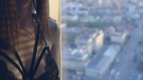 Beautiful girl in black lingerie is looking through the window Stock Footage