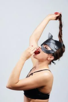 Beautiful girl in a cat mask. seductively posing with strawberries in front o Stock Photos