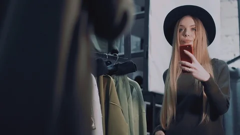 Beautiful girl chooses clothes in the store. Shoots himself on a smartphone Stock Footage 86654053