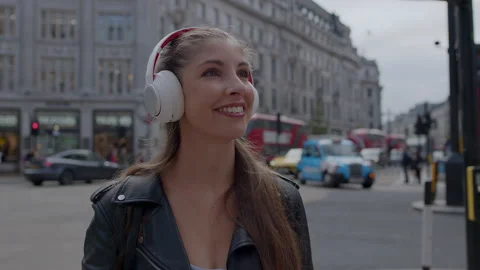 Beautiful girl in city ctr using noise cancelling headphones Stock Footage 162397026