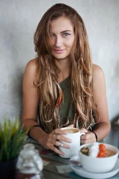 Beautiful girl with cup of coffee and muesli bowl is sitting in a cafe Stock Photos