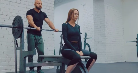 Beautiful girl doing basic exercises, bench press barbell lying. Girl shakes the Stock Footage 122704865