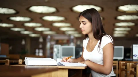 Beautiful girl doing notes from a book in the library 2 Stock Footage 66474297