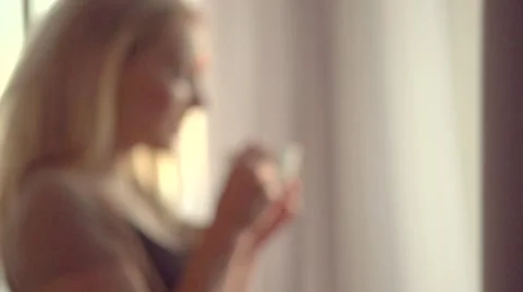 Beautiful girl drinking morning coffee or tea and looking out the window Stock Footage 59088924