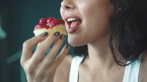 The beautiful girl eats an appetizing cake and drinks coffee. Female lips Vidéo 77428627