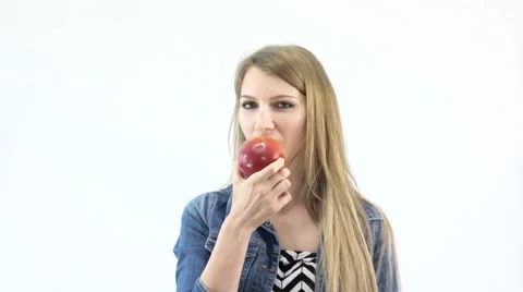 Beautiful girl eats a red apple on a white background UHD 4K Stock Footage 62895395