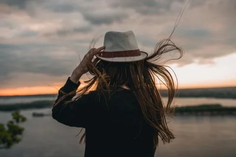 Beautiful girl in the hat looks at the sunset Stock Photos