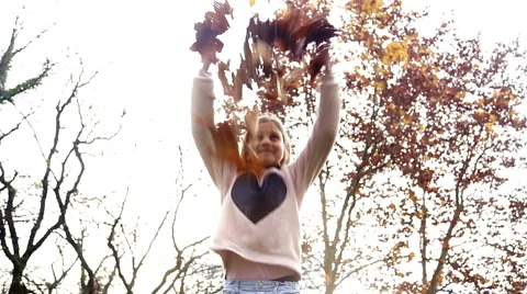 Beautiful girl having fun throwing leaves in the air Stock Footage 59553956