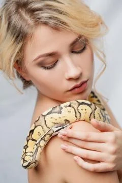 Beautiful girl  holding a python, which wraps around her body Foto stock