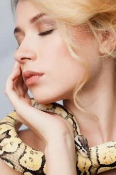 Beautiful girl  holding a python, which wraps around her body Foto stock