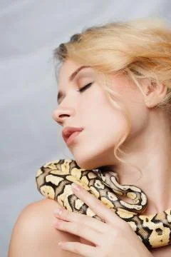 Beautiful girl  holding a python, which wraps around her body Foto stock
