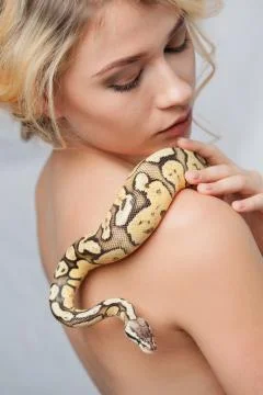 Beautiful girl  holding a python, which wraps around her body 写真素材