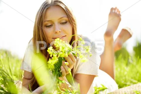 A beautiful girl lying on grass with flowers Stock Photos