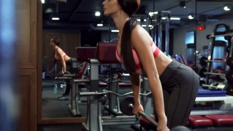 Beautiful girl performs forward bends with a barbell in hands Stock Footage 83382208