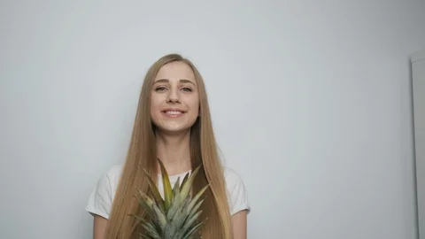 Beautiful girl with pineapple posing in front of camera in bright room Stock Footage 128971754