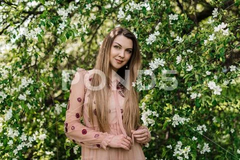 Beautiful girl in a pink dress looks at us against the background of white Stock Photos