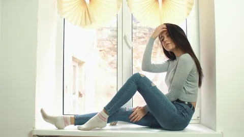 Beautiful girl posing half on the windowsill Stock Footage
