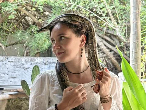 Beautiful girl with a python on the shoulders and on the head. A petting zoo  Stock Photos
