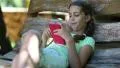 Beautiful girl with red smartphone sits on the swing bench HD Footage