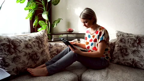 Beautiful girl relaxing on sofa using laptop and smiling at camera Stock Footage 88349150