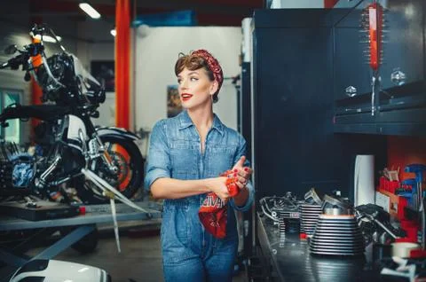 Beautiful girl repairs a motorcycle in a workshop, pin-up style, service and  Stock Photos