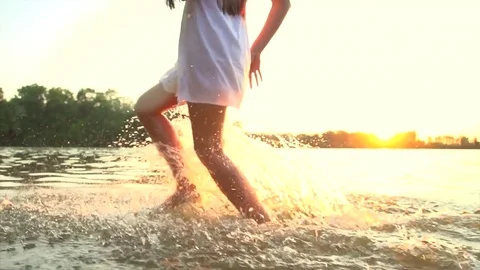 Beautiful girl in short white dress running on sunset beach Stock Footage