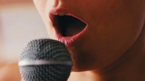 Beautiful girl sing something in a hand-held microphone Stock Footage
