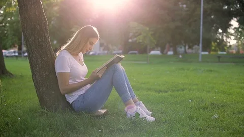 Beautiful girl sitting under the tree an... | Stock Video | Pond5