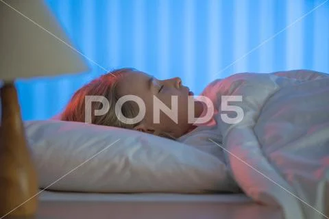 The beautiful girl sleeping on the bed. Evening night time Stock Photos