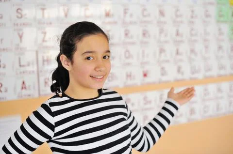 Beautiful girl standing in front of a periodic table of elements Stock Photos