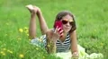 Beautiful girl in sunglasses with red smartphone lies on the grass HD Footage