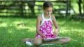 Beautiful girl with tablet computer sits on the grass HD Footage