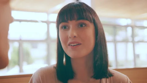 Beautiful girl talking with a guy at a table in interior cafe with soft day ligh Video stock 199453039