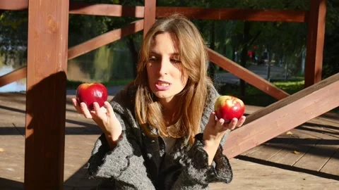 Beautiful girl with two apples does not know which to eat Stock Footage 142467350