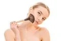 The beautiful girl using a cosmetic brush on the white background Photo